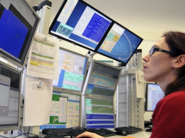 A young female scientist in the lab at DESY, looking at different screens with data