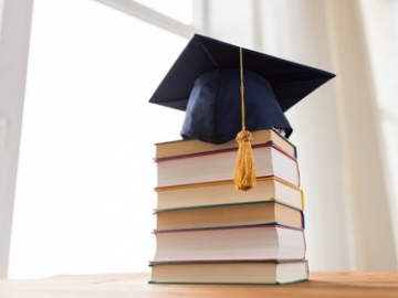 A doctoral cap lying on a pile of books