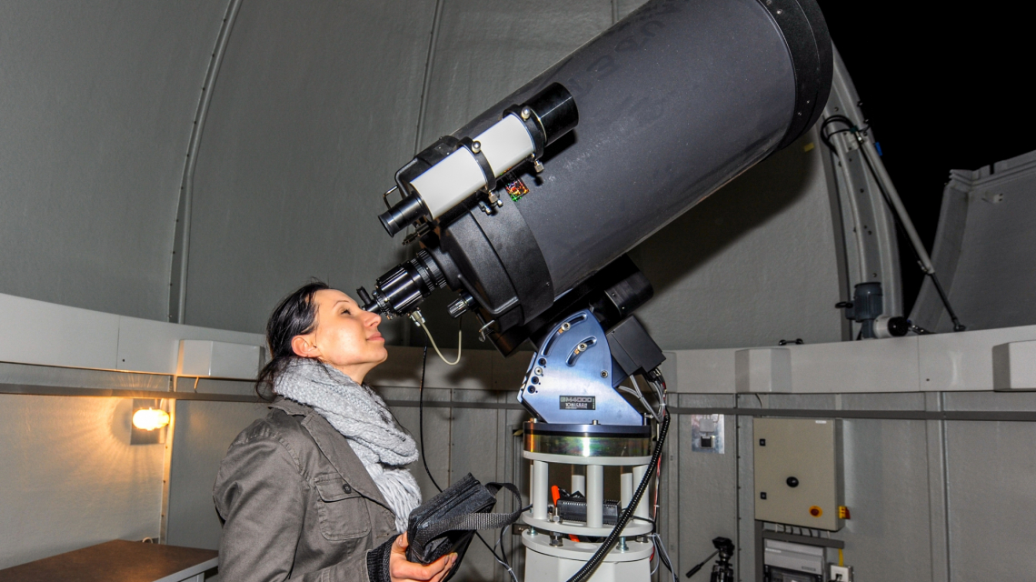 Eine Frau blickt durch ein Teleskop an der  Übungssternwarte der Universität Potsdam.